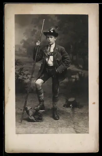 Foto-AK Junge mit Wanderstock und Tracht vor einer Studiokulisse