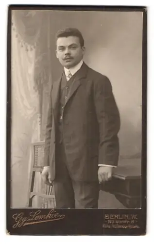 Fotografie Gg. Lemkie, Berlin-W, Portrait junger Mann im eleganten Anzug an Tisch gelehnt