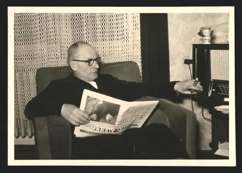 Fotografie Schmitt & Schmitt, Köln, Herr liest Zeitung Die Welt & sucht Frequenz im Radio / Radioempfänger