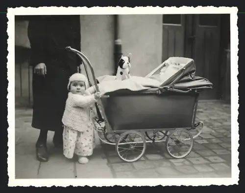 Fotografie Kleinkind nebst Kinderwagen und Stoffhund