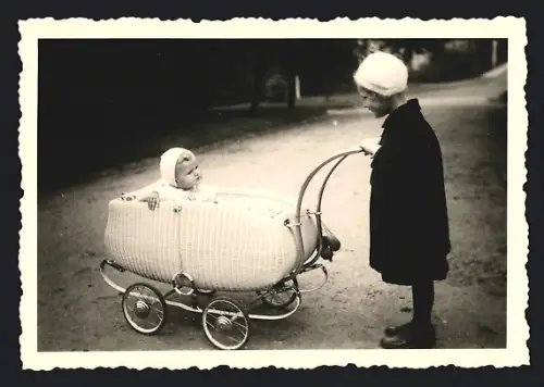 Fotografie Mädchen schiebt Baby im Kinderwagen