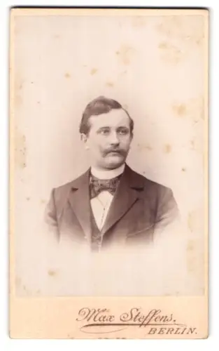 Fotografie Max Steffens, Berlin, Portrait Mann mit gewelltem Haar und Schnauzer