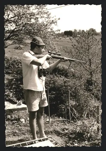 Fotografie Rotholz, Berlin, Jäger mit Gewehr und Zielfernrohr schiesst vom eigenen Garten aus
