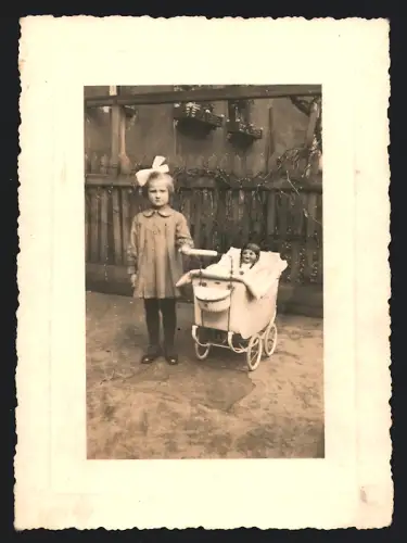 Fotografie Mädchen mit Haarschleife & Puppe im Puppenwagen