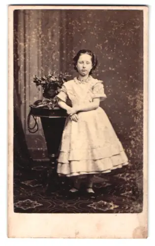 Fotografie Th. North, Dublin, Grafton Street 71, Mädchen im eleganten Kleid neben Tisch