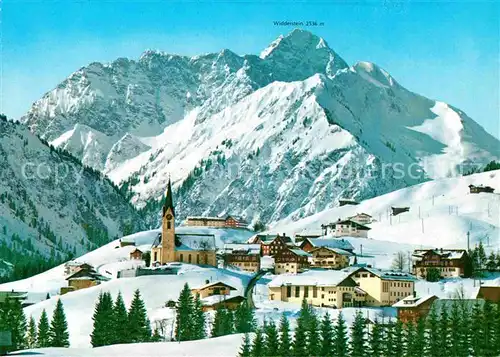 AK / Ansichtskarte Hirschegg Kleinwalsertal Vorarlberg Ortsansicht mit Kirche Winterpanorama mit Widderstein Kat. Mittelberg