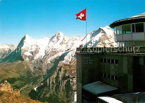 AK / Ansichtskarte Schilthorn Muerren Bergstation Bergbahn Piz Gloria mit Eiger Moench und Jungfrau Berner Alpen Schweizer Flagge Kat. Schilthorn