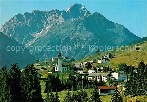 AK / Ansichtskarte Hirschegg Kleinwalsertal Vorarlberg Ortsansicht mit Kirche Blick zum Widderstein Allgaeuer Alpen Kat. Mittelberg