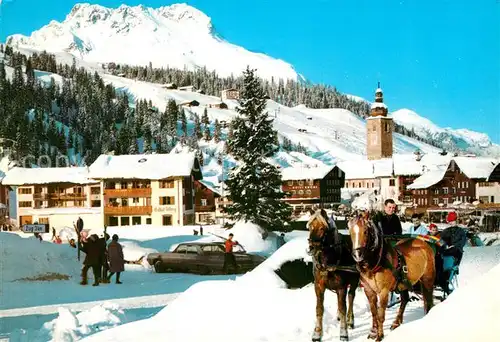 AK / Ansichtskarte Lech Vorarlberg Ortsmotiv mit Kirche Pferdeschlitten Blick zum Karhorn Lechquellengebirge Winterpanorama Kat. Lech