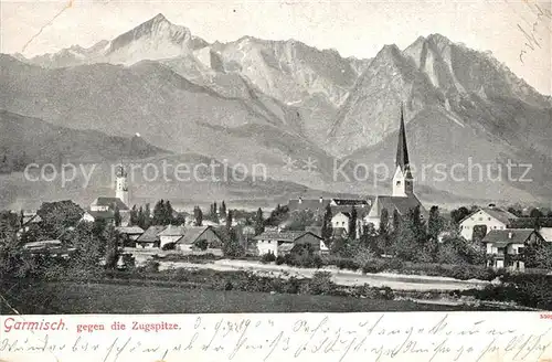 AK / Ansichtskarte Garmisch Partenkirchen Ortsansicht mit Kirche gegen Zugspitze Wettersteingebirge Garmisch Partenkirchen