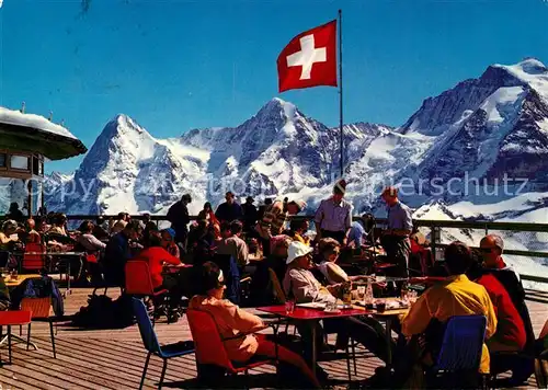 AK / Ansichtskarte Muerren_BE Schilthornbahn Berggaststaette Sonnenterrasse Eiger Moench Jungfrau Berner Alpen Schweizer Flagge Muerren_BE