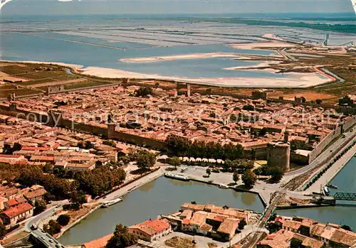 AK / Ansichtskarte Aigues Mortes_Gard La ville du Roy Saint Louis Tour de Constance au fond les marais salants vue aerienne Aigues Mortes Gard
