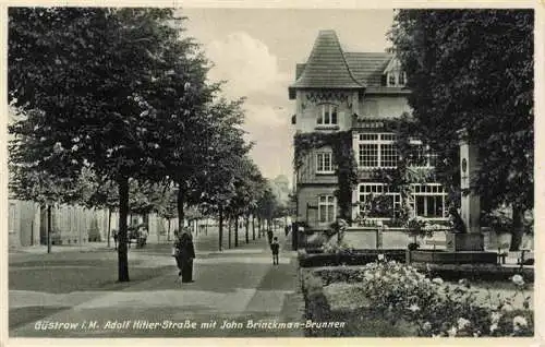 AK / Ansichtskarte  Guestrow_Mecklenburg_Vorpommern Strassenpartie mit John Brinckman-Brunnen