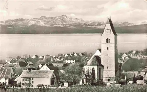 AK / Ansichtskarte Hagnau Bodensee Teilansicht Kurort mit Kirche Blick gegen Schweizer Alpen