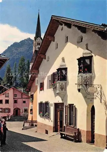 AK / Ansichtskarte Scuol Schuls GR Dorfgasse Kirchturm Engadin-Haeuser Heilbad Geranien Berge Pflasterstrasse Erker