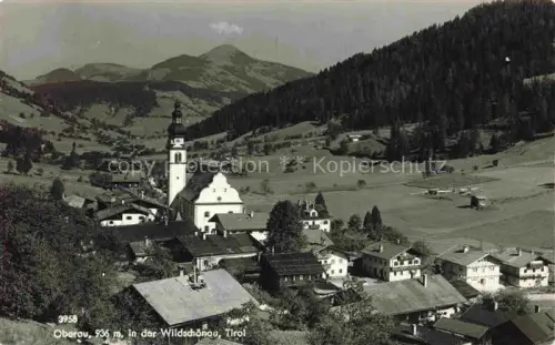 AK / Ansichtskarte Oberau Tirol Wildschoenau Tirol AT Wildschoenau Kirchturm Dorfansicht Bergpanorama Bergwiesen Wald Bauernhaeuser