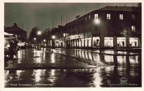 AK / Ansichtskarte Umea Sweden Kungsgatan Kvaellsbelysning Nachtaufnahme Regen Schaufenster Strassenlampen