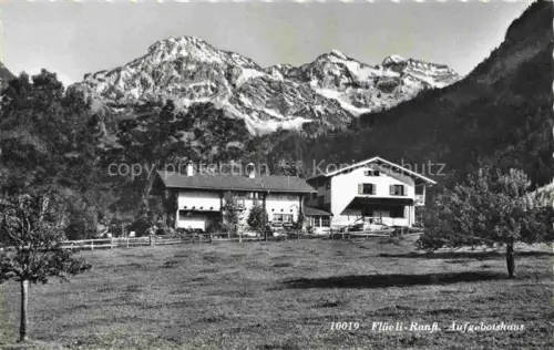 AK / Ansichtskarte Flueeli-Ranft Fluehli-Ranft OW Aufgebotshaus Bauernhaus Bergpanorama Wiese Baeume Alpen