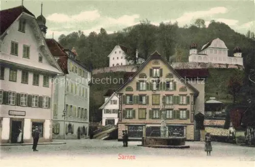 AK / Ansichtskarte Sarnen Obwalden OW Dorfplatz Brunnen Haeuser Kapelle Huegel Geschaefte Passanten