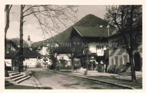 AK / Ansichtskarte Ruhpolding Bayern Dorfstrasse Haeuser Berge Kirchturm Baeume Oberbayern