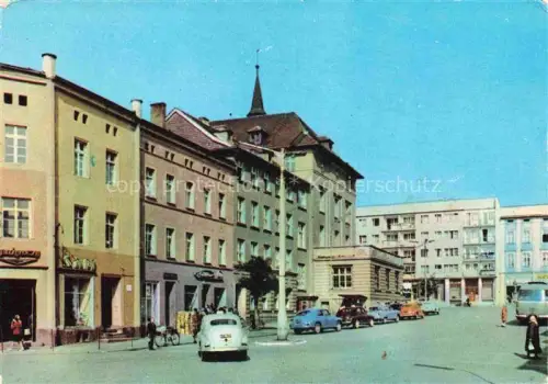 AK / Ansichtskarte Rogoznica Gross Rosen Plac-Przyja?ni-Polsko-Radzieckiej Stadtplatz Geschaefte Autos Kirchturm Wohnhaeuser Passanten
