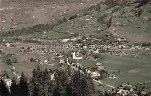 AK / Ansichtskarte Lenk Simmental BE Dorfansicht Berner-Oberland Kirche Haeuser Wiesen Nadelwald Vogelperspektive