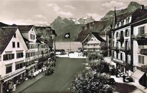 AK / Ansichtskarte Brunnen  SZ Gitschen Urirotstock Hauptstrasse Schweizer-Fahne Vierwaldstaettersee Berge Haeuser Geschaefte