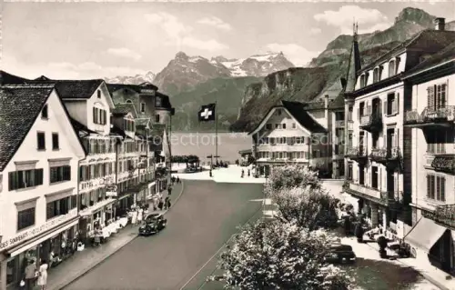 AK / Ansichtskarte Brunnen Vierwaldstaettersee SZ Gitschen Urirostock Vierwaldstaettersee Platz Schweizer-Fahne Hotel Souvenirladen Dorf