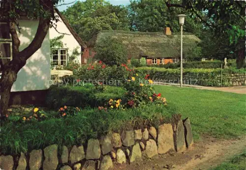 AK / Ansichtskarte Keitum Sylt Dorfpartie Friesenhaus Reetdach Steinmauer Blumengarten Dorfstrasse Sylt