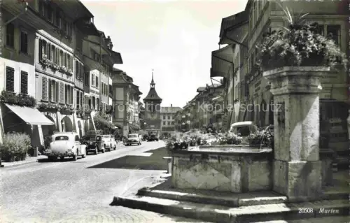 AK / Ansichtskarte Murten Morat FR Hauptgasse Zeitglockenturm Brunnen Autos Geschaefte Strassenszene