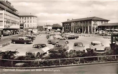 AK / Ansichtskarte RuessELSHEIM Main Gross-Gerau Hessen Bahnhofsplatz Parkplatz Autos Bahnhof Opelstadt Geschaefte 1950er