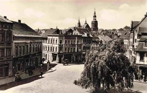 AK / Ansichtskarte Eisleben August-Bebel-Plan Lutherstadt Kirchturm Marktplatz Weidenbaum Geschaefte Kopfsteinpflaster