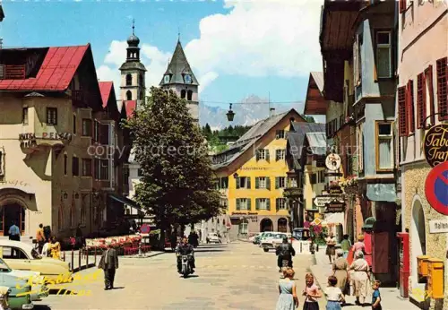 AK / Ansichtskarte Kitzbuehel Tirol AT Stadtplatz Wilder-Kaiser Kirchturm Hotel-Reisch Strassenszene Autos Touristen Tabak