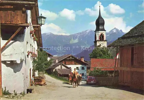 AK / Ansichtskarte Fiss Oberinntal Tirol AT Dorfstrasse Kirchturm Berge Reiter Bauernhoefe Laterne Blumenschmuck Oberinntal