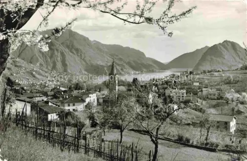 AK / Ansichtskarte Comano LUGANO TI Kirchturm See Berge Stadtpanorama Fruehling Weinberge Kirschbluete