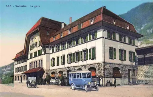 AK / Ansichtskarte Vallorbe Orbe VD La-Gare Bahnhof Bahnhofsgebaeude Autobus Autos Berge koloriert