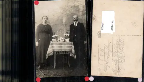 670334,Foto Ak Paar b. Tisch mit Fotos Blumen stehend