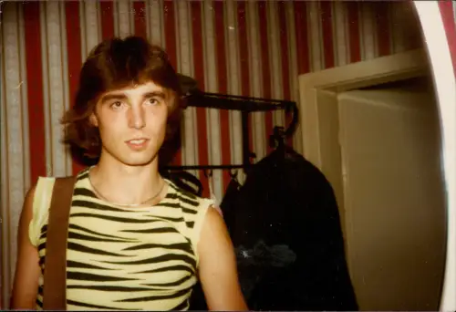 Porträt eines jungen Mannes im Zebra-Shirt vor rot gestreifter Tapete 1980
